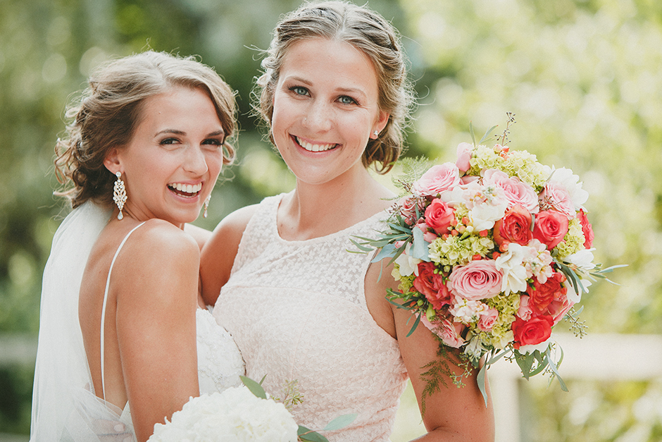 A bride and her girlfriend holding a bouquet of flowers.