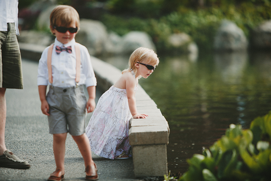 A little girl with sunglasses, stares into a pond.