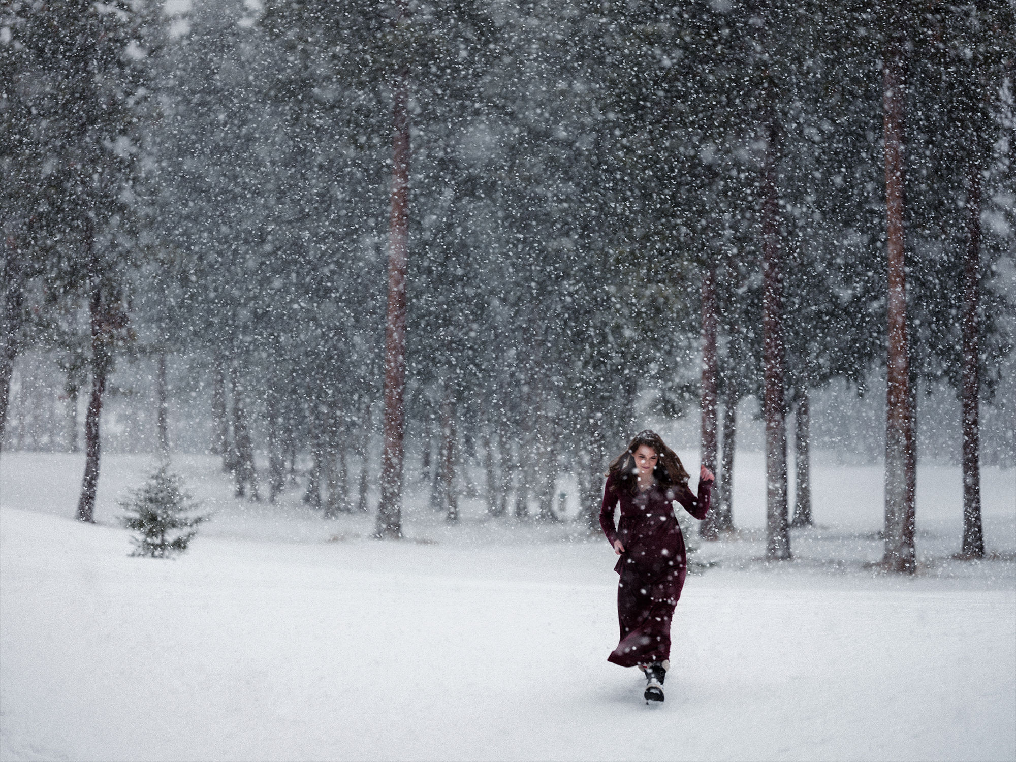 Girl in red dress runs in a snowy forest