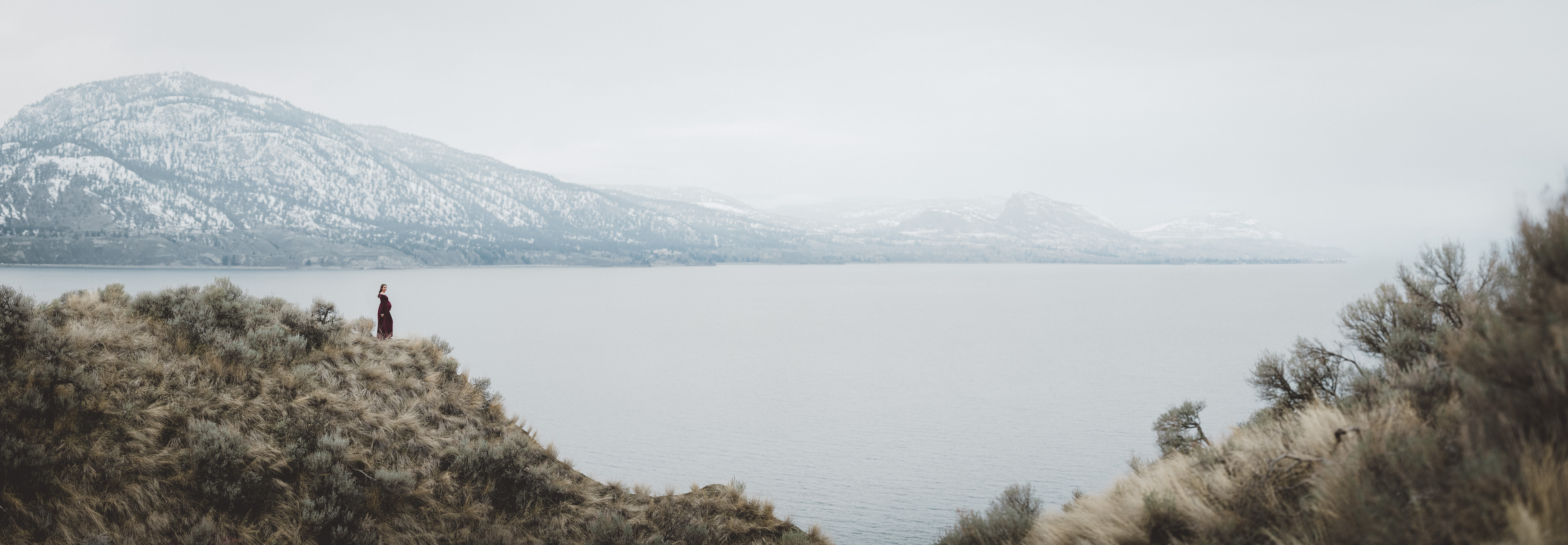 Okanagan Lake with a pregnant woman standing on a cliff