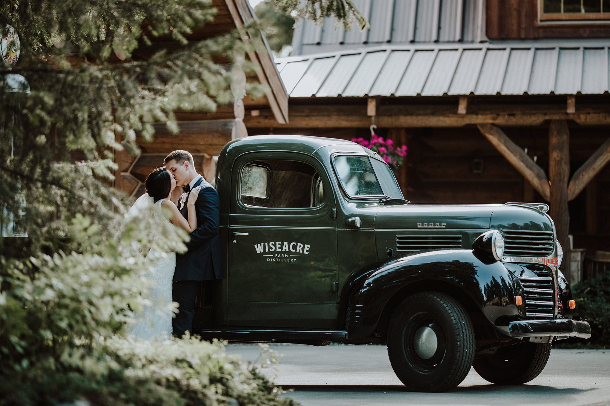 A bride and groom have a romantic moment by a vintage pickup truck.