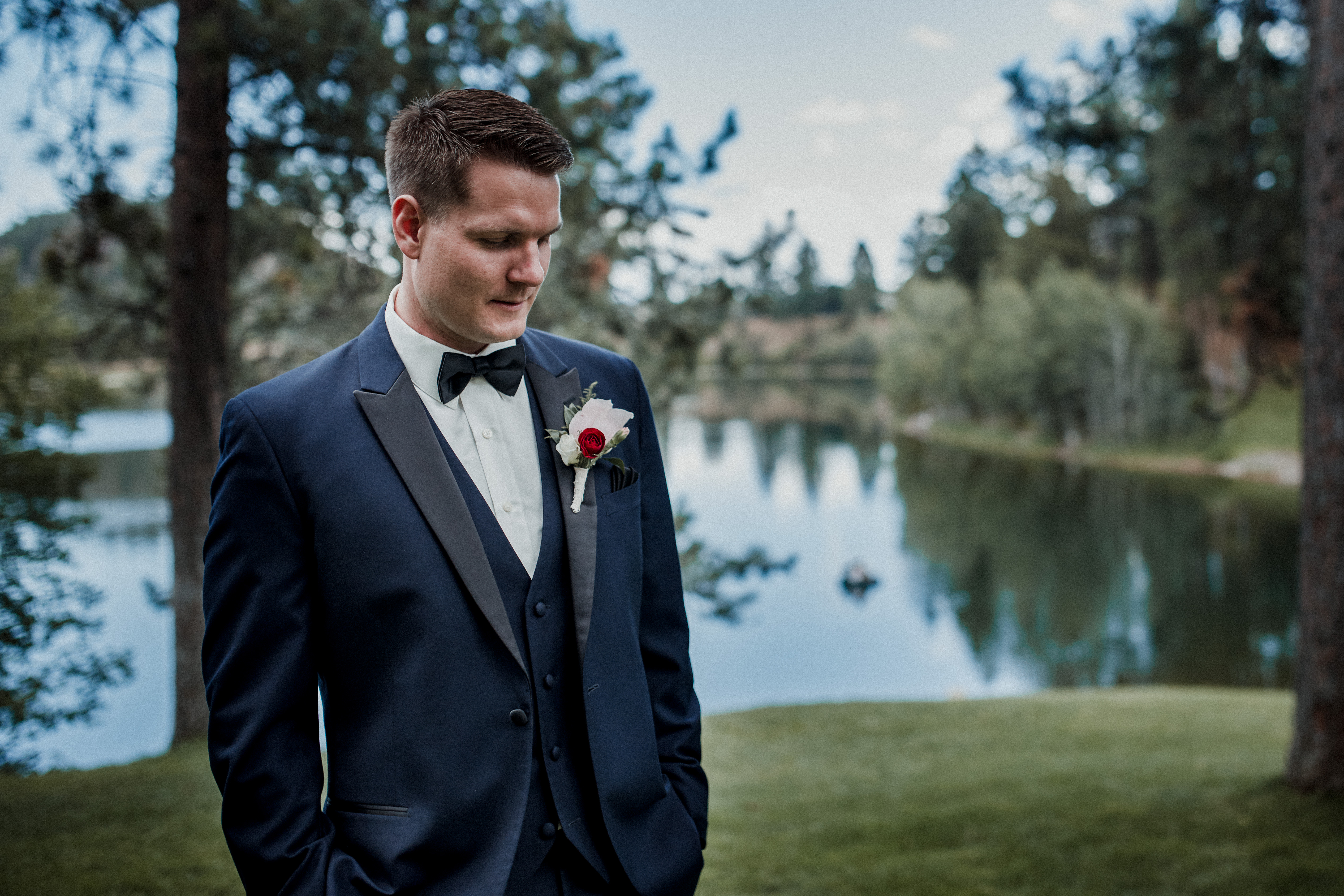 A groom looks forelorn as he awaits by a pond for his bride to arrive.