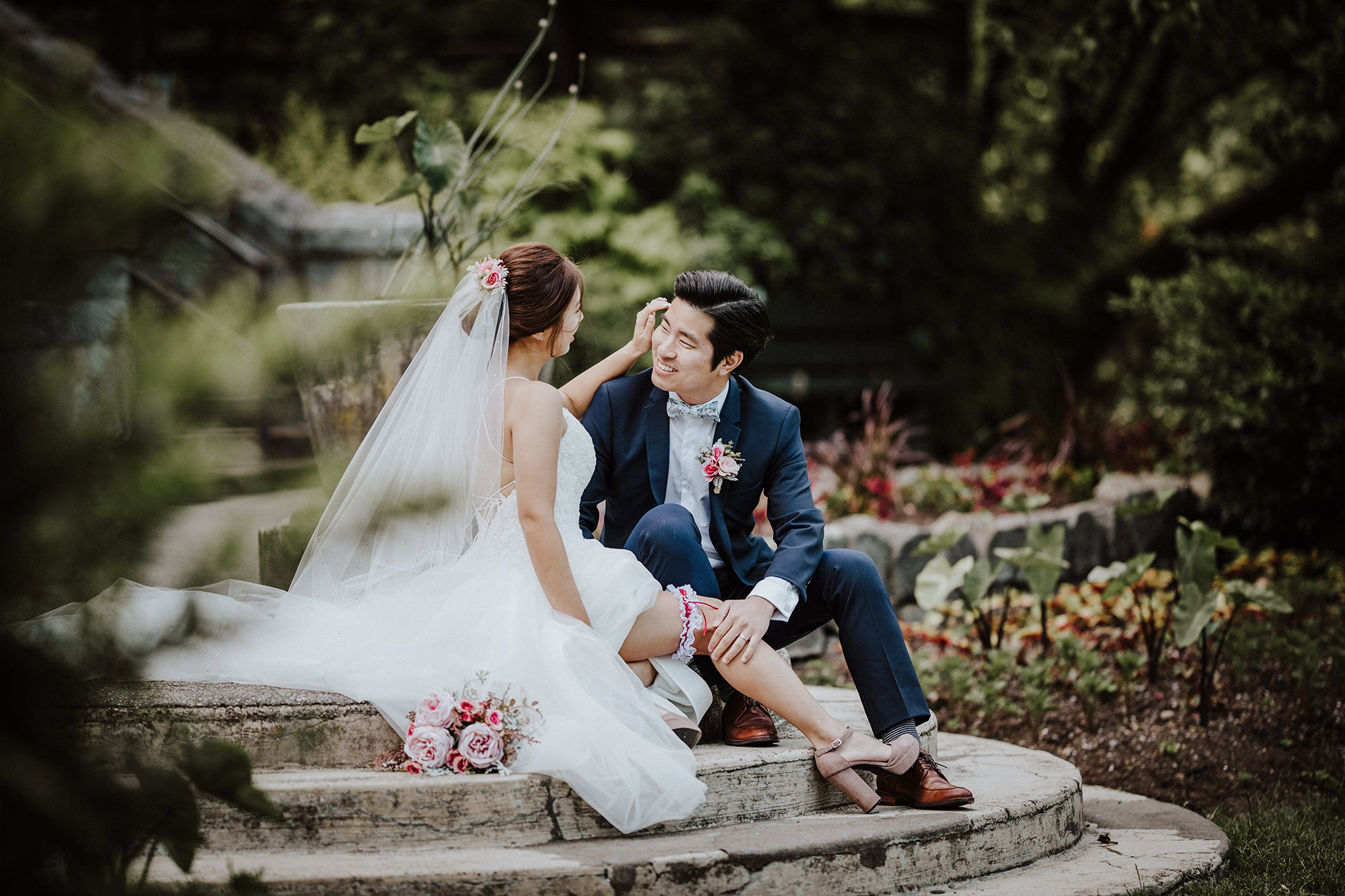 Bride and groom sit on stone steps while he caresses her leg