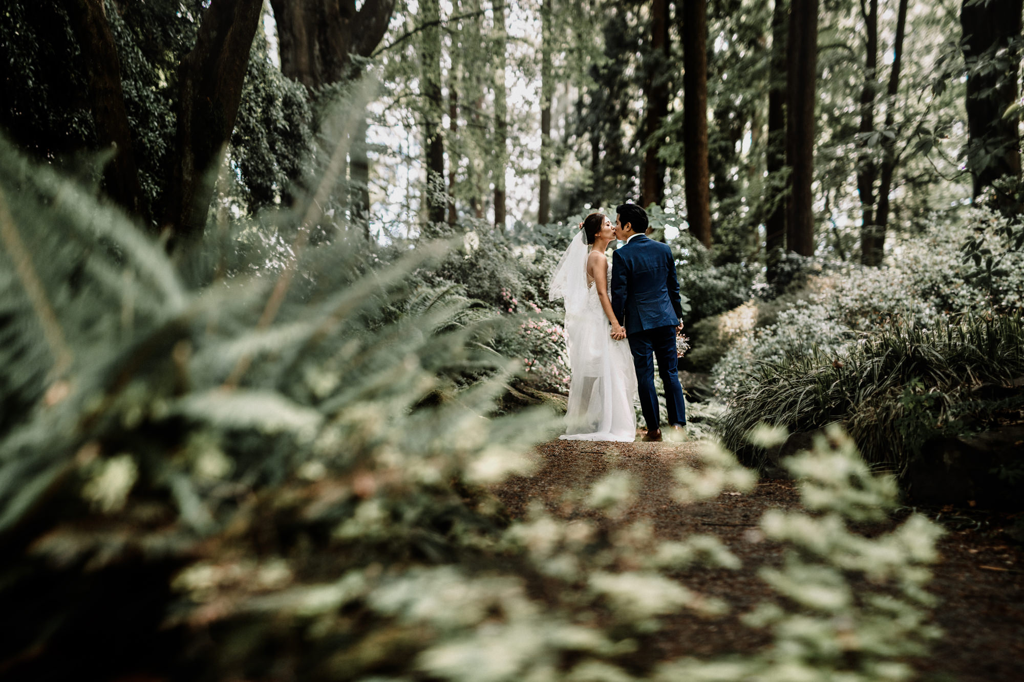 Wedding couple share a kiss on a forest path
