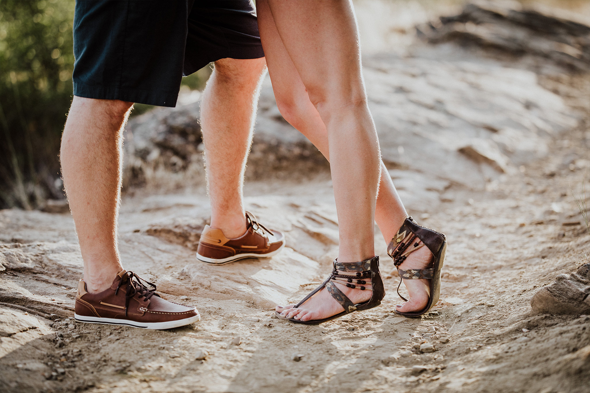 Man and woman's legs, feet in sandals on dirt path