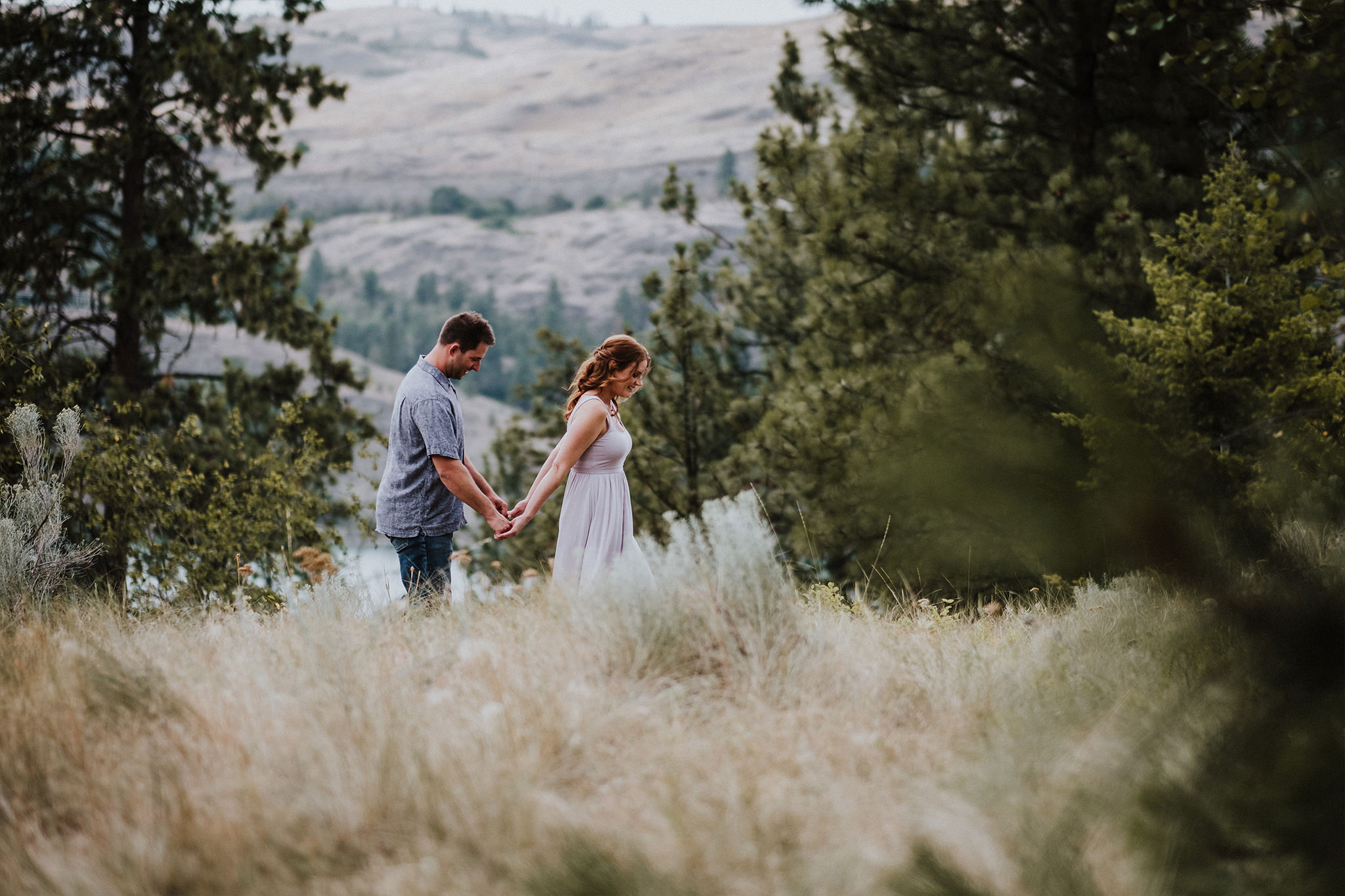 Girl leads her boyfriend by the hand in a field of tall grass