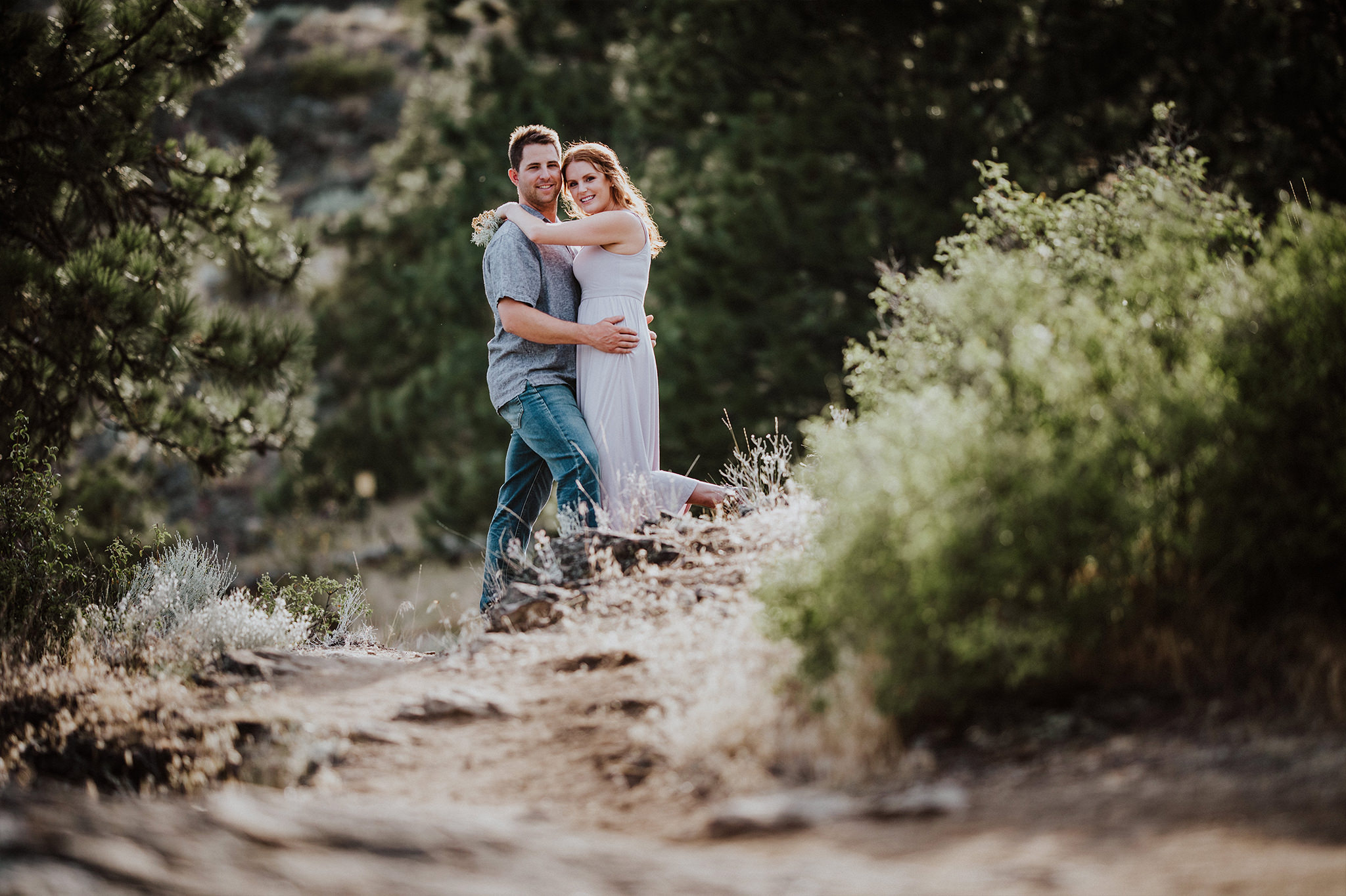 Couple poses for a photo while walking along a dirt path