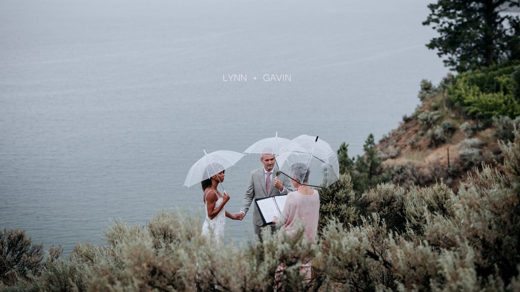 A couple perform their marriage ceremony on a cliff in the rain.